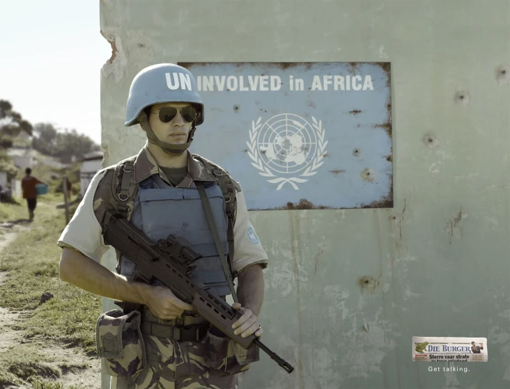 a man in uniform with a rifle next to a sign