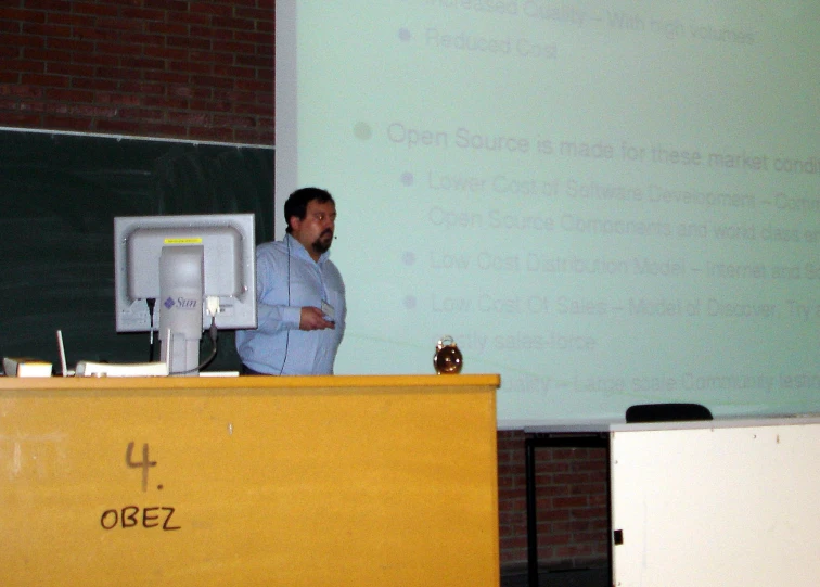 man stands next to podium in front of projector screen