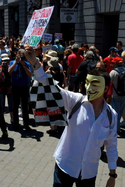man in a clown mask standing with a sign and people