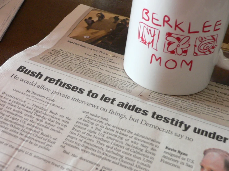 newspapers surrounding the table with a coffee mug and cell phone