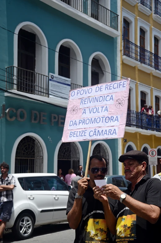 two men holding a protest sign on a city street