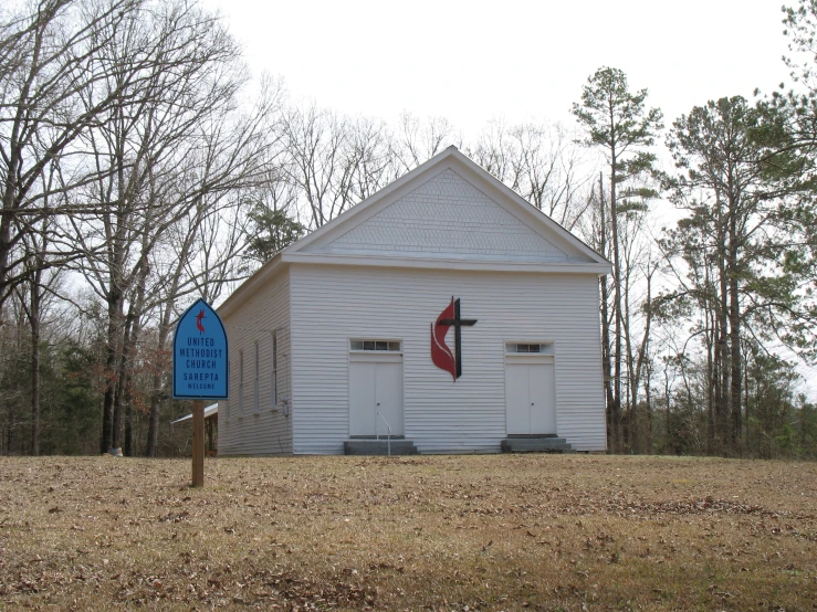 a white church with a red flag and two blue gates