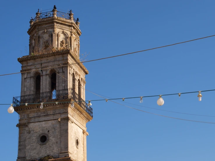 two white balls hanging from wires with a clock tower