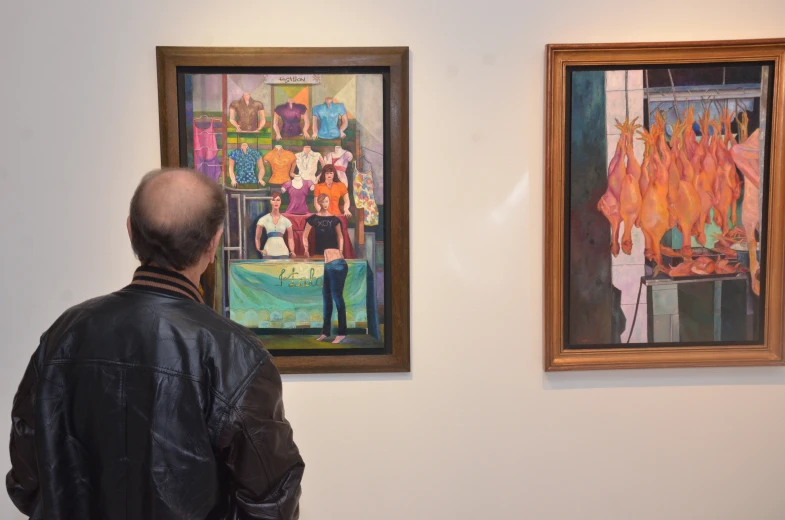 man looking at paintings on the wall during the day