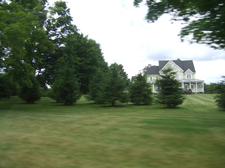 large house with trees next to it in a field