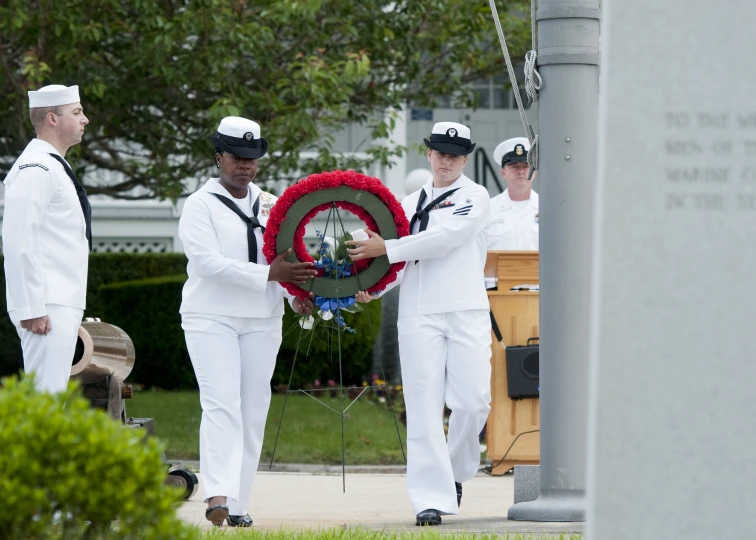 men in uniform holding a wreath at the end of a memorial