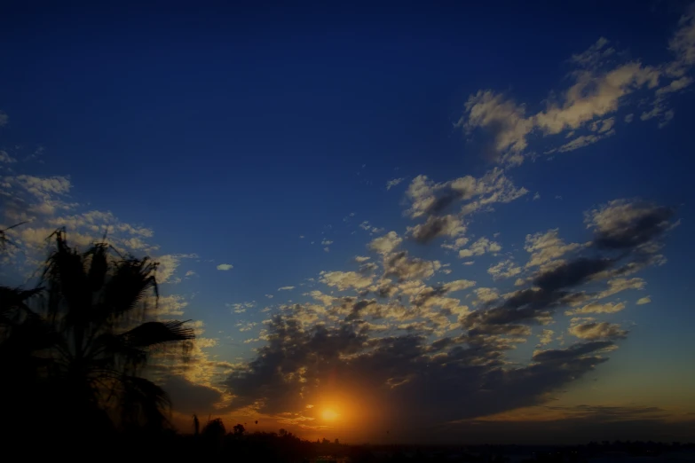 the sun is setting behind a cloud covered sky