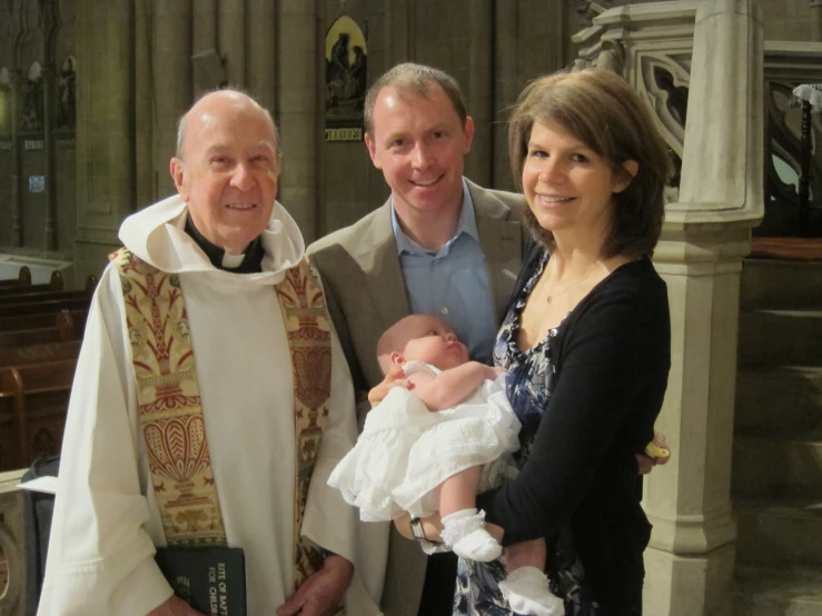 a woman, man and baby pose for a po inside a church