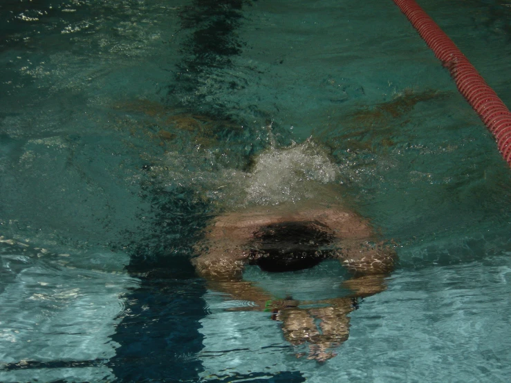 a swimmer is floating upside down with his head above water