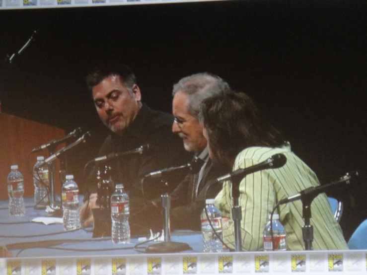 there are people on the screen behind a group of microphones