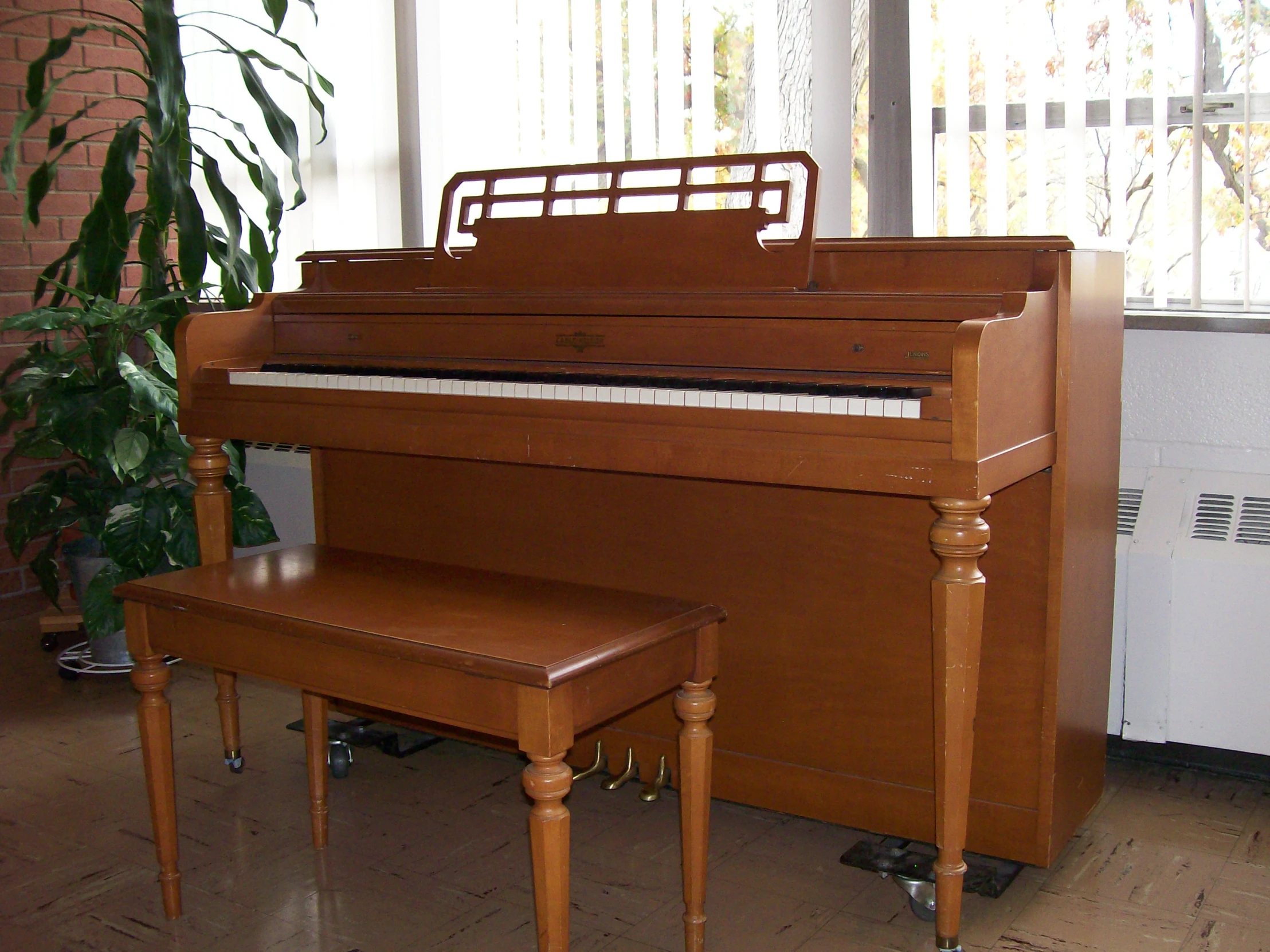 an upright piano is near a plant with a white piano keyboard