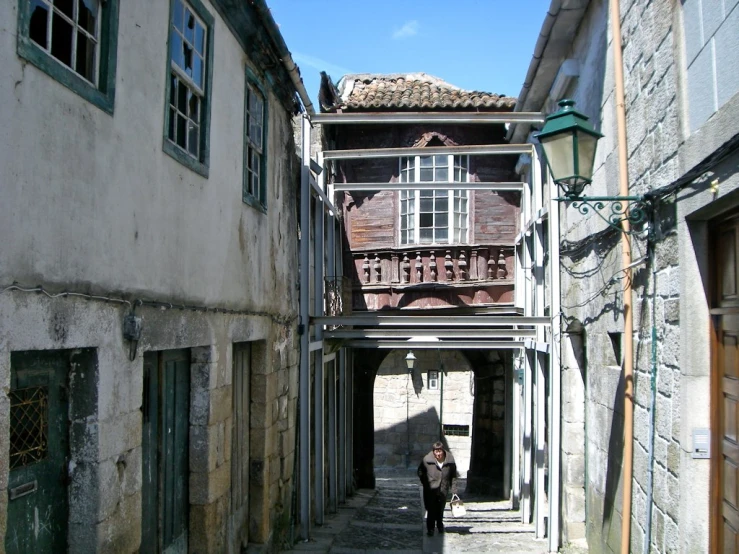 a woman walking down an alley way near buildings