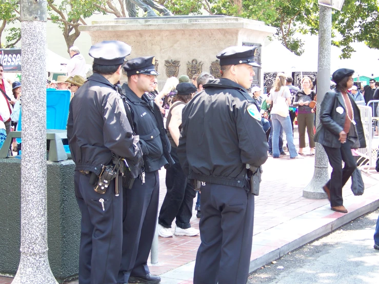 three police officers standing next to a pole