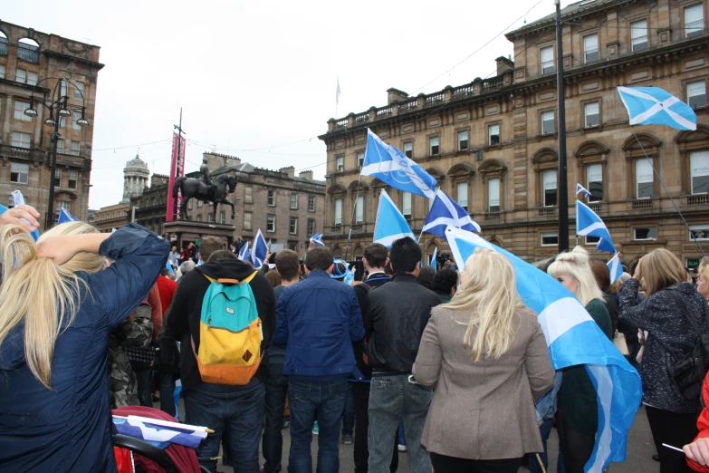 people walk through a city with scotland flags