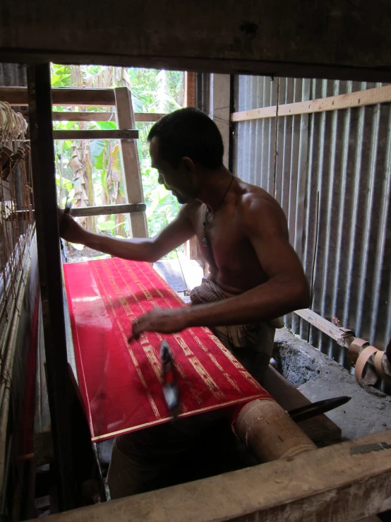 a man is painting a piece on red fabric