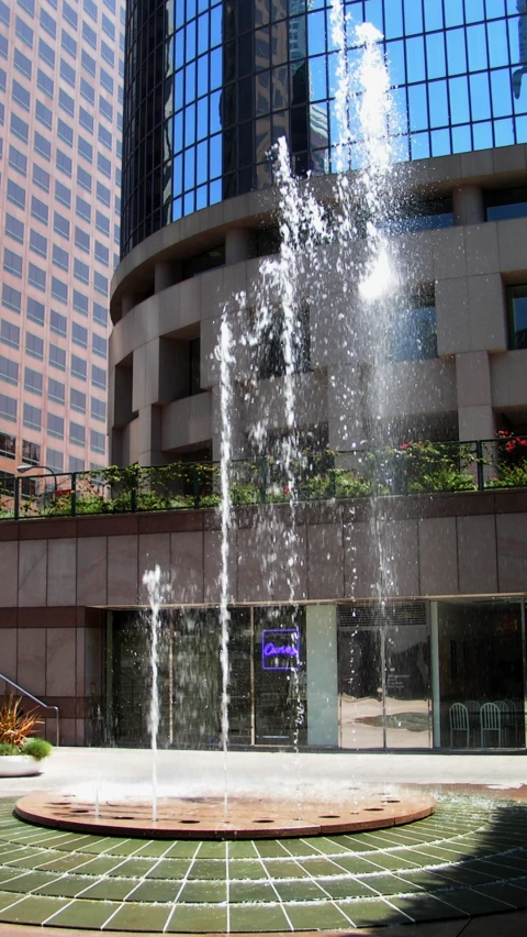 a fountain spouting water into a square in front of a large building