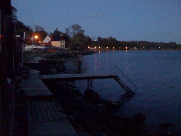 a long dock on the water at dusk with lights shining on it