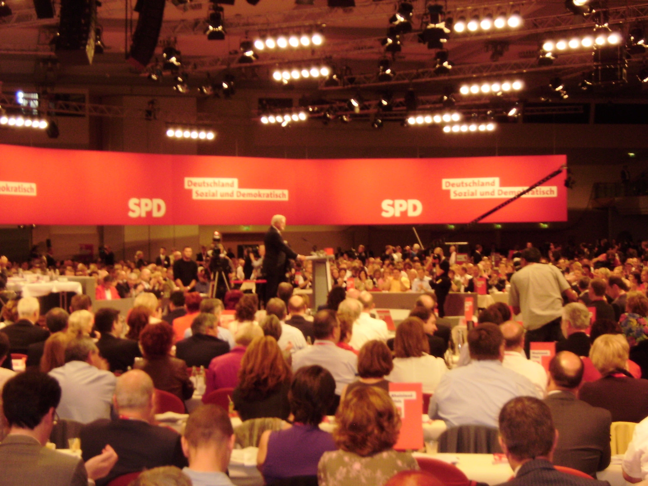 a group of people sitting in an auditorium with speakers at the front