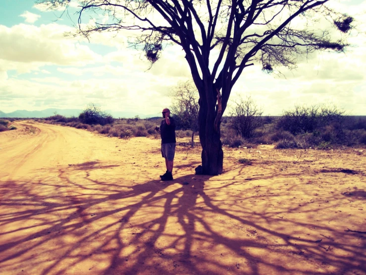 there is a man standing in the middle of a dirt road