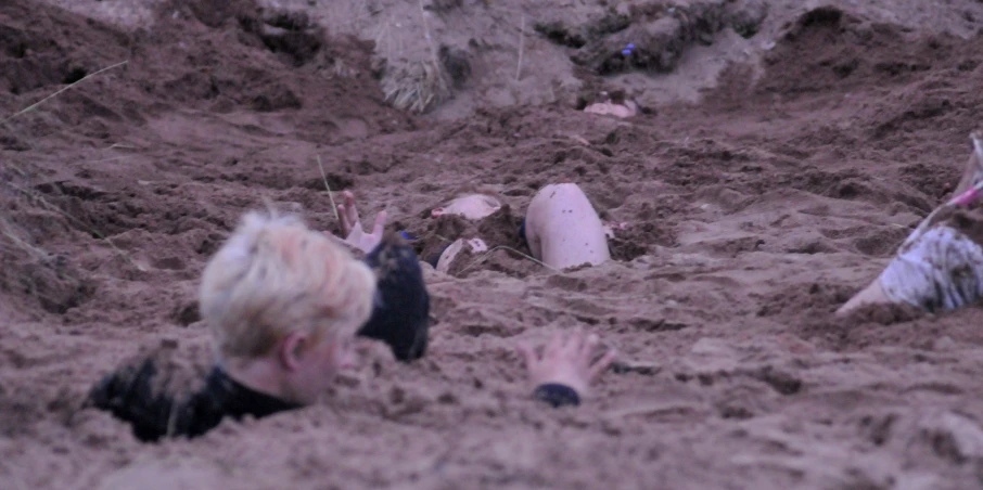 a child sitting in some deep mud near an object