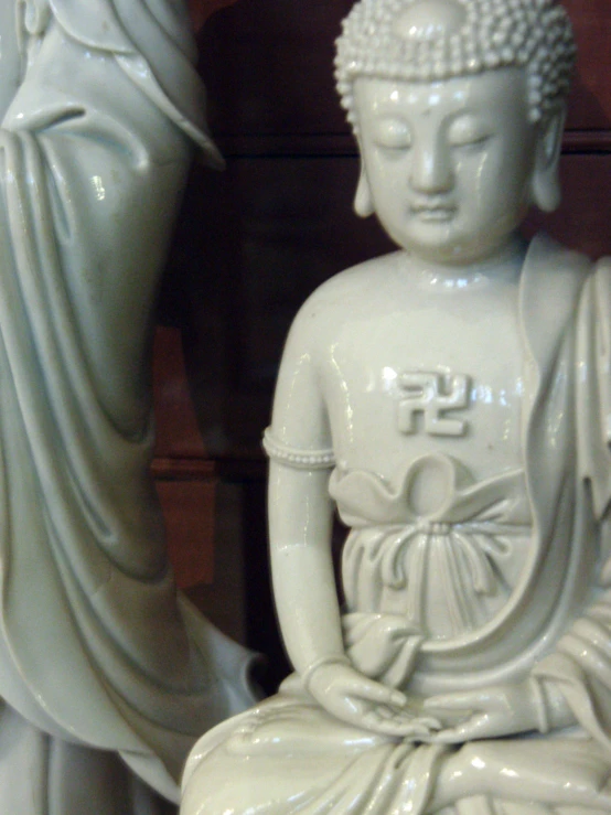 a statue is sitting next to a statue of buddha