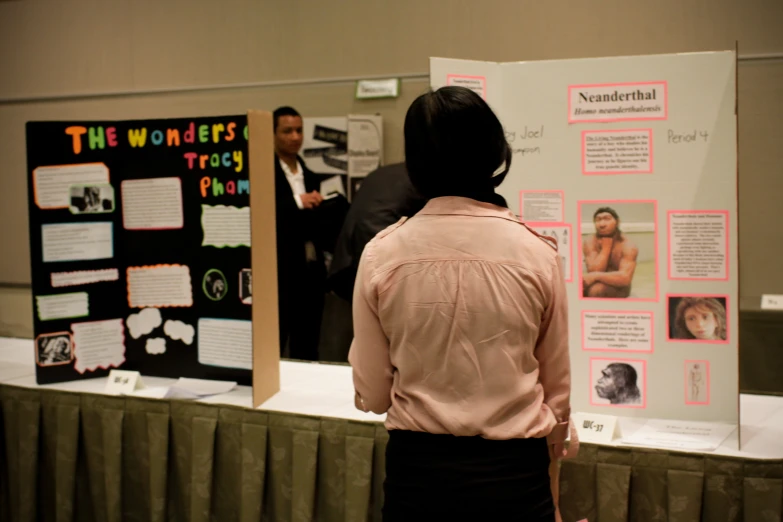 a woman standing at a desk next to poster