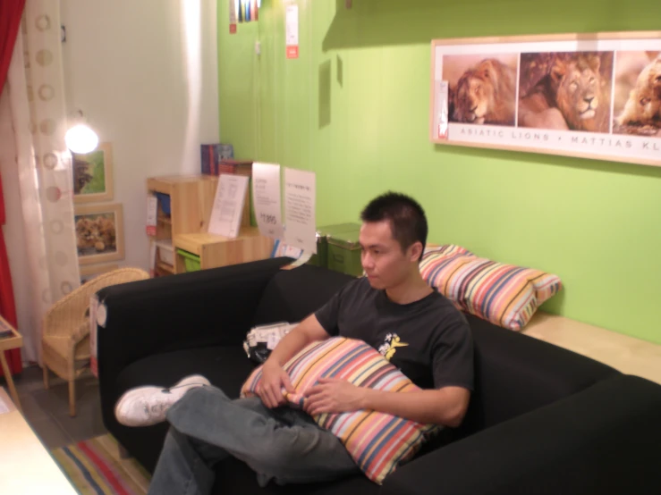 a man sitting on a black couch in a green room