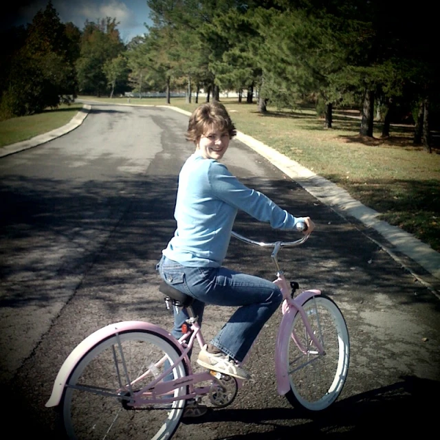 girl riding pink bike in residential neighborhood on open street