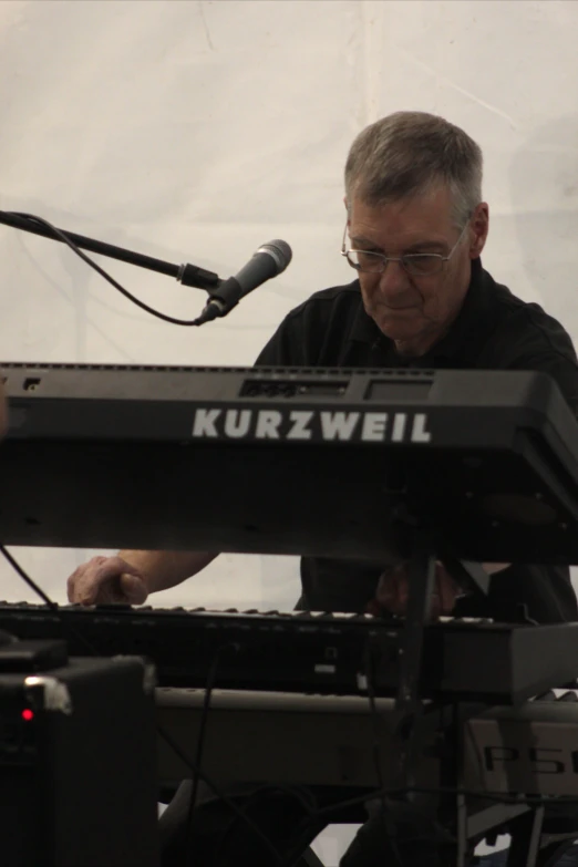a man sitting at a keyboard with a microphone and speaker