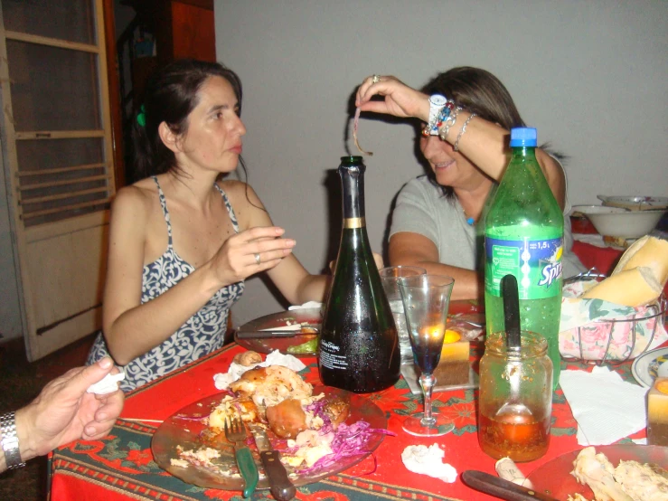 two people are sitting at a table with food and wine