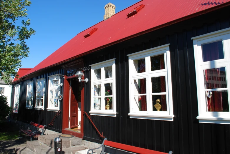 a small black house with three windows and a red roof