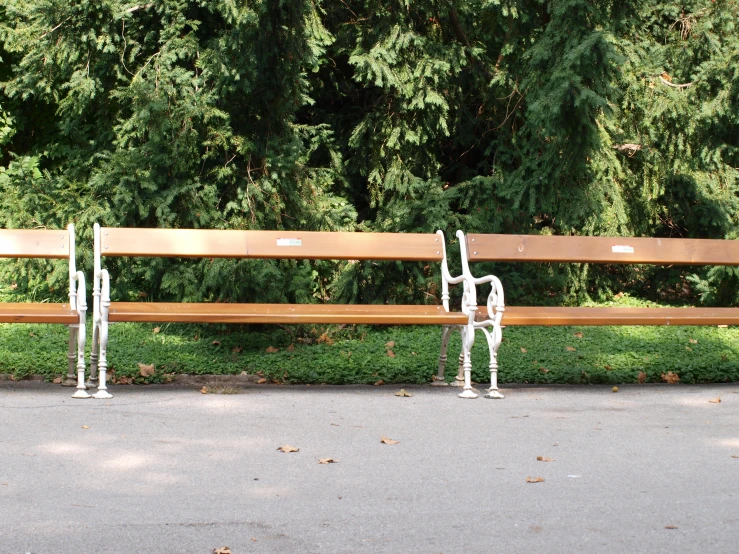 two wooden park benches with white sculptures attached to them