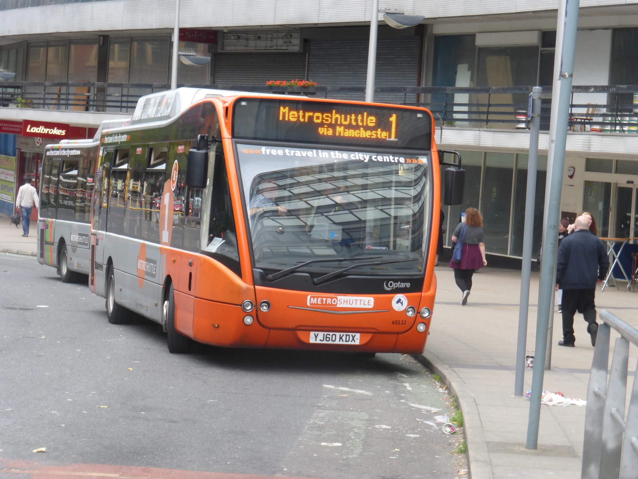 the orange city bus is coming down the street