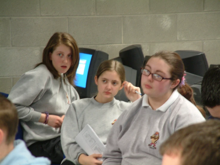 two girls look on as another girl listens