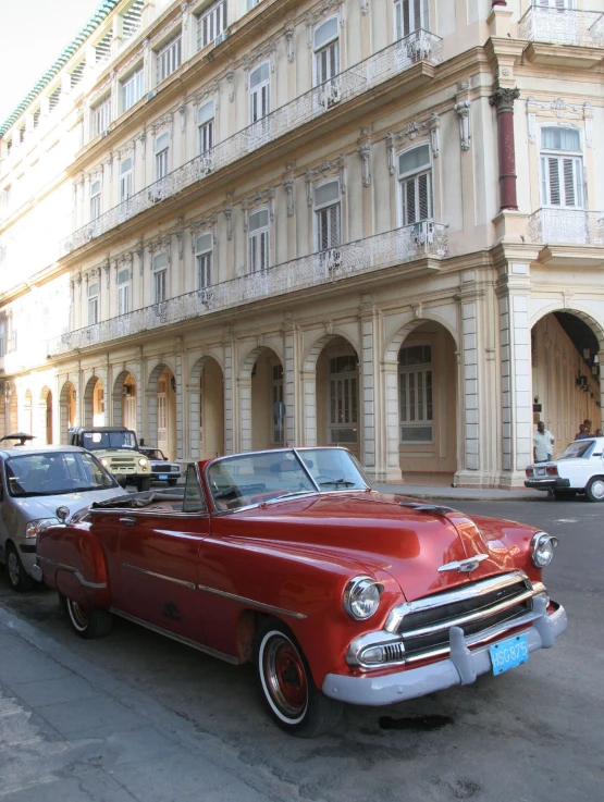 a very old car is parked near a tall building