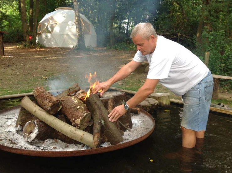 an old man is cooking soing in a wood fired oven