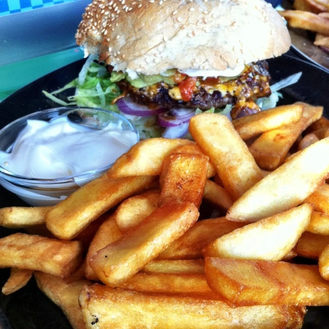 french fries on a black plate with a hamburger and lettuce