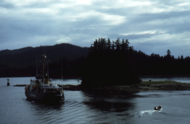 a small boat sailing on the water near a hill