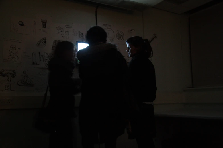 three people are in the dark near a wall