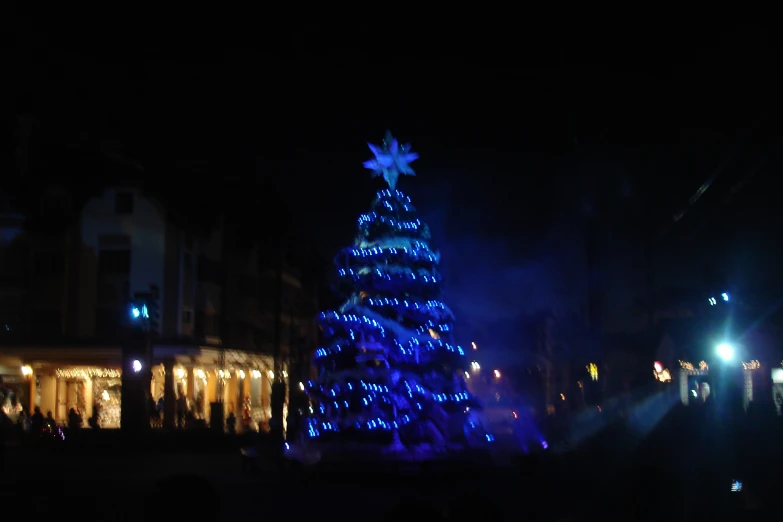 a large christmas tree lit up on a street at night