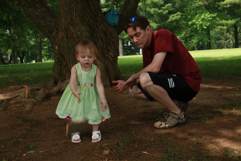 a man kneeling down to pick up a little girl's shoe