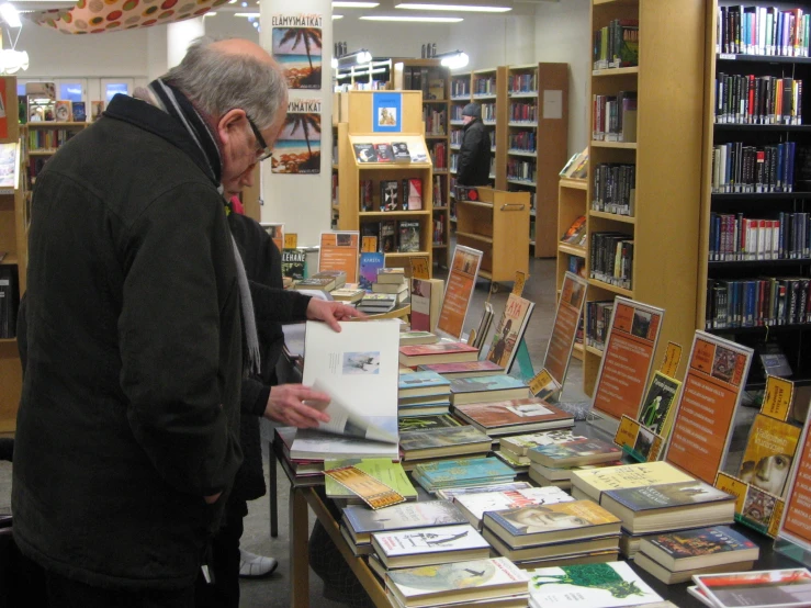 a man stands next to a table covered in books