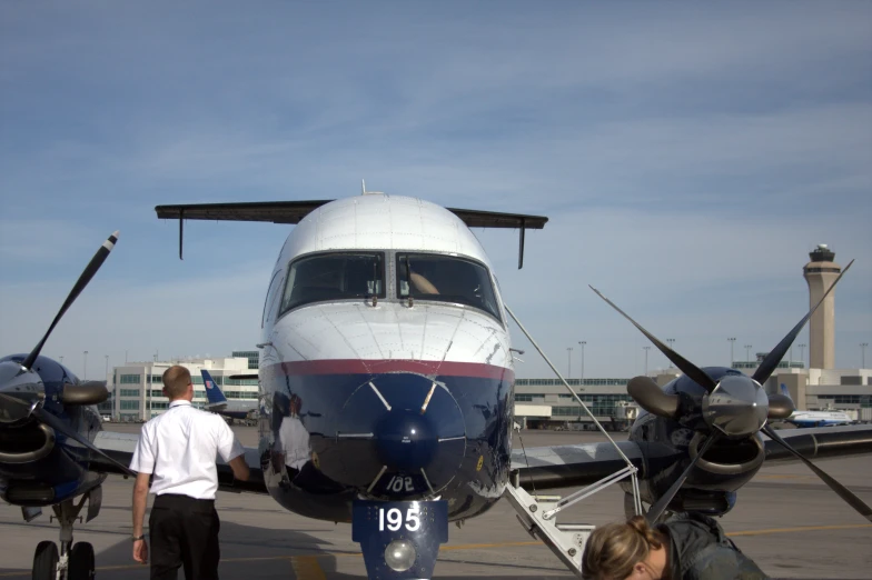 some people and two small planes parked on the runway