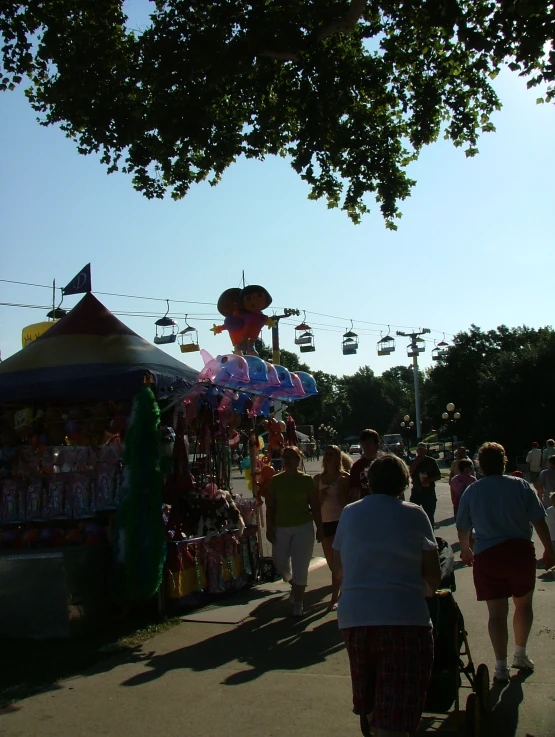 people walk through a fair while a float floats above