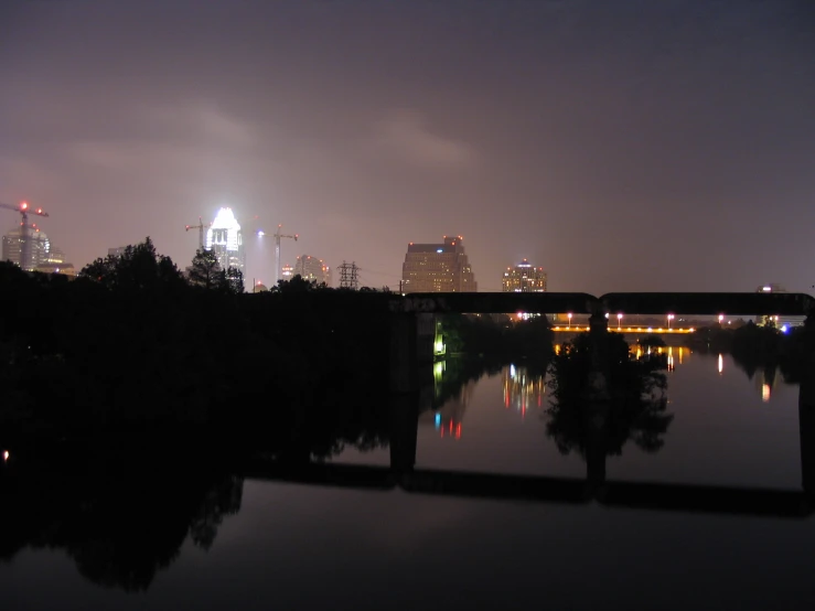 city at night time with skyscrs reflected in water