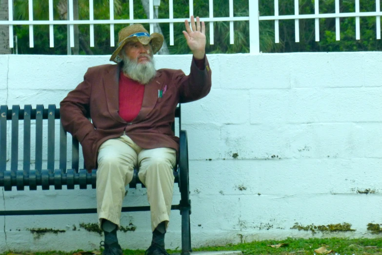 a man is sitting on a bench waving at the camera