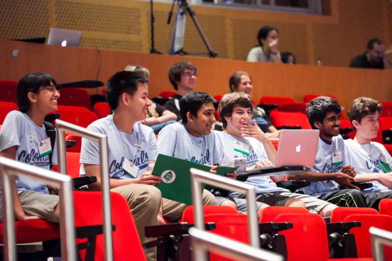 many people in white shirts are sitting on the seats