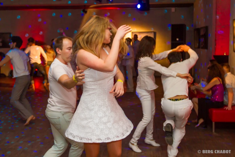 several people wearing white dance in a group