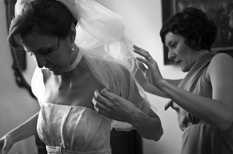 the bride fixes her veil as the maid helps