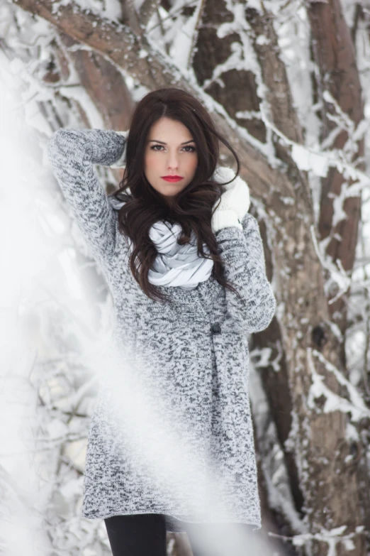 a woman standing in the snow near a tree